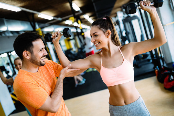 Personal trainer instructing a beautiful woman in modern gym - Fotó, kép