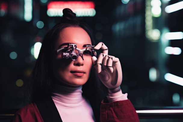 houkutteleva aasialainen tyttö futuristinen käsi ja silmä proteesi kadulla illalla, kaupungin tulevaisuuden konsepti
 - Valokuva, kuva