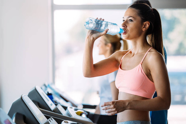 Sporty woman hydrating during workout in gym - 写真・画像