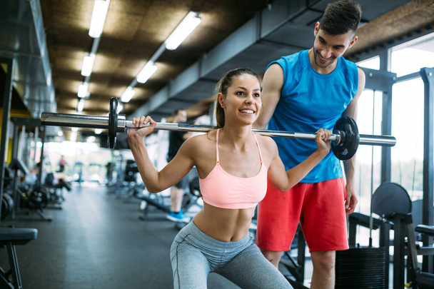 Personal trainer instructing a beautiful woman in modern gym - 写真・画像