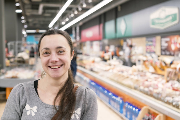 Весела жінка середнього віку з довгим волоссям в супермаркеті
 - Фото, зображення