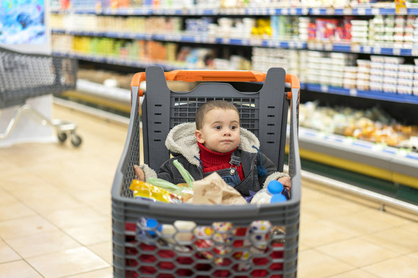 Chariot complet avec de la nourriture au supermarché. Dans le chariot se trouve un bébé
. - Photo, image