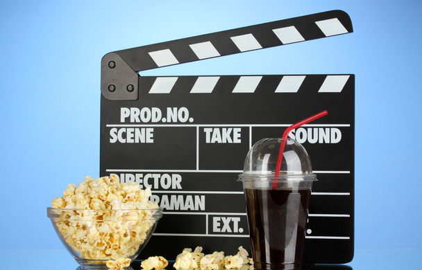Movie clapperboard, cola and popcorn on blue background - Fotoğraf, Görsel