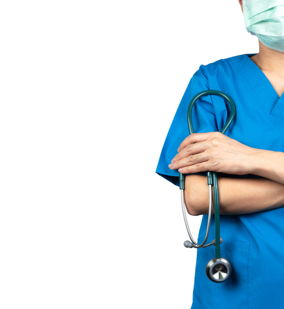 Kirurgi lääkäri käyttää sininen pensaikot paita univormu ja vihreä kasvonaamio. Lääkärin seistä kädet ristissä ja käsi kädessä stetoskooppi. Terveydenhuollon ammattilainen. Lääkärilääkäri seisoo luottavaisena. Luota
. - Valokuva, kuva