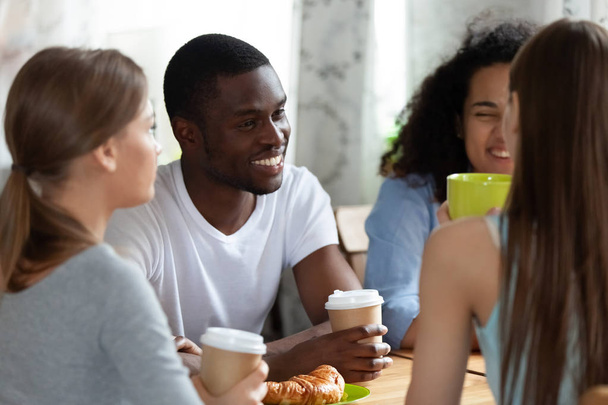 Black man and girls sitting drinking coffe chatting in cafe - Foto, Bild