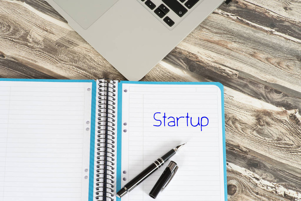 Un computer su un tavolo da ufficio e una cartella con la parola Startup
 - Foto, immagini