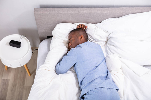High Angle View Of Young African Man Sleeping On Bed In Bedroom - Valokuva, kuva