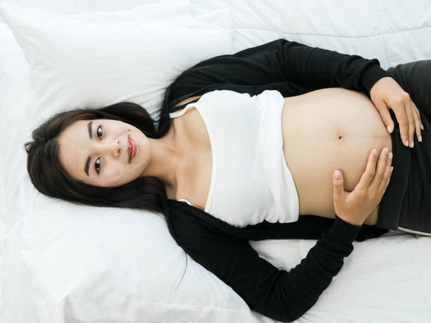 Asian pregnant woman resting on bed at home, lifestyle concept. - Valokuva, kuva