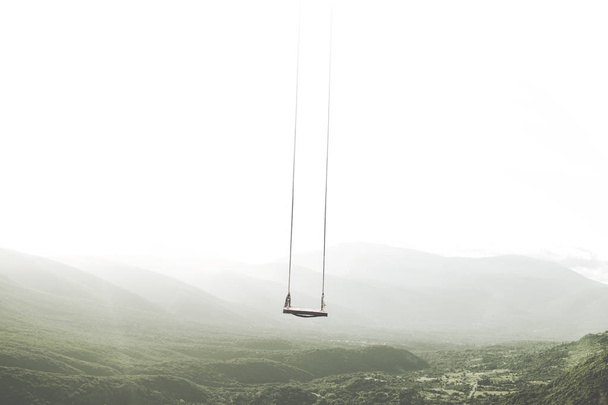 surreal mountain landscape with a swing that moves in the sky - Photo, Image