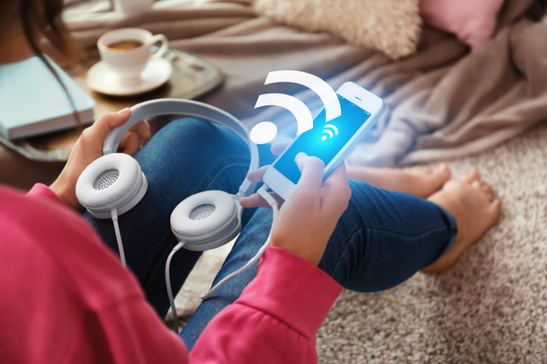 Woman with headphones and smartphone using free Wi-Fi at home - Photo, image