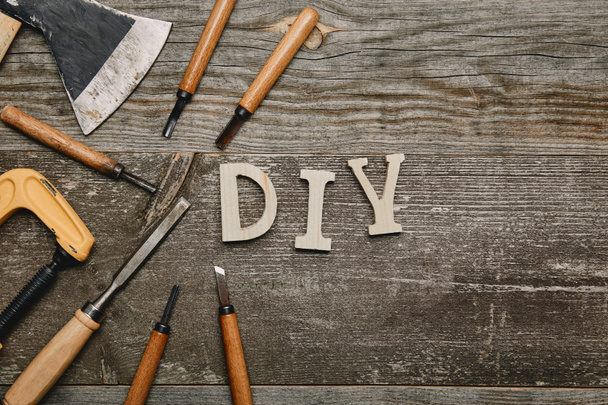 Top view of different carpentry tools and diy sign on wooden background - Foto, imagen