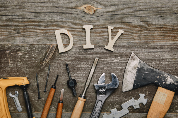 Flay lay met verschillende timmerwerk tools en diy teken op houten achtergrond - Foto, afbeelding