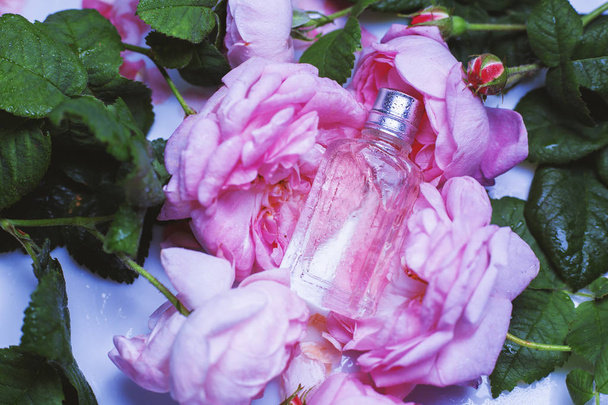 μικρό μπουκάλι αρώματος με ροζ λουλούδια  - Φωτογραφία, εικόνα