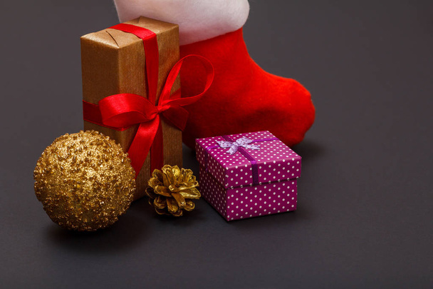 クリスマス装飾。ギフト ボックス、サンタさんのブート、おもちゃボール、黒い背景に自然な円錐形は。クリスマスのグリーティング カードの概念. - 写真・画像
