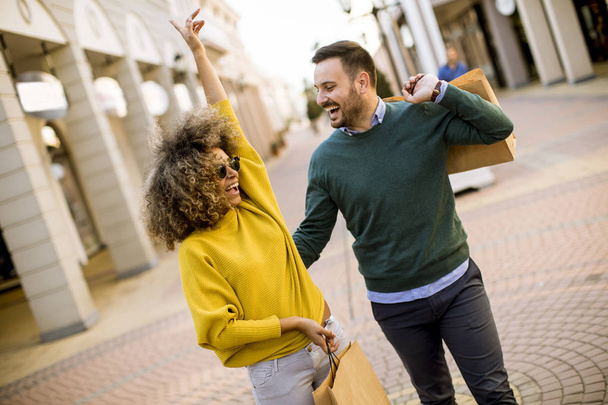 schönes junges multiethnisches Paar mit Taschen beim Einkaufen - Foto, Bild