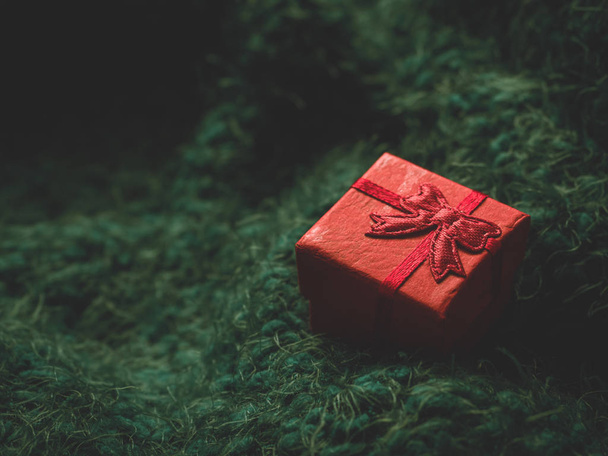 Red gift box on green soft background. Surprise, comfort, warmth, care concept - Фото, зображення