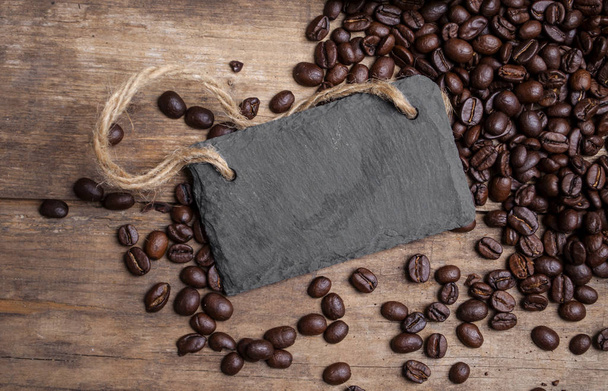 Chalkboard with coffee beans and a cup of coffee on natural brown wood - Фото, зображення