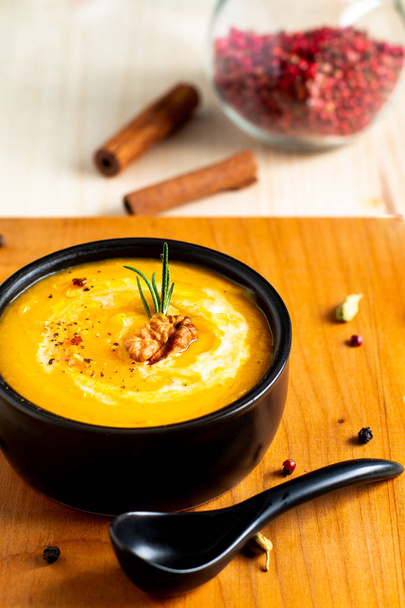 Концепция осенней зимней еды Тыквенный или ореховый суп в черной миске на деревянном фоне
 - Фото, изображение