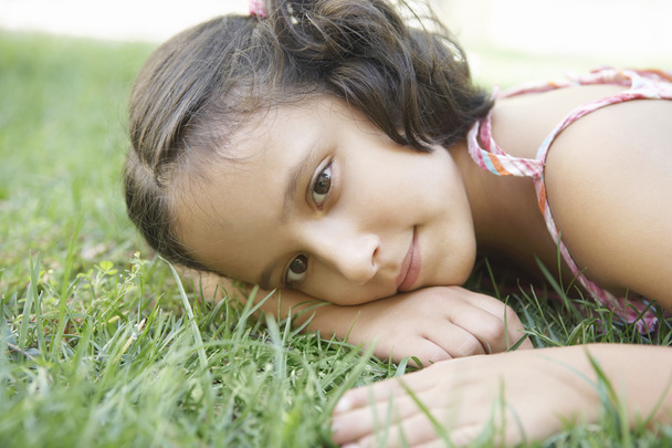 Young girl laying down on green grass - Photo, Image