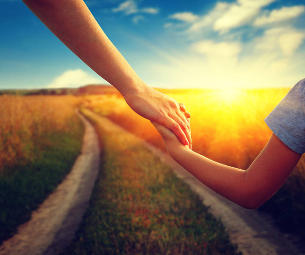 Mains de se tenir mutuellement dans le champ sur la route et le soleil - Photo, image