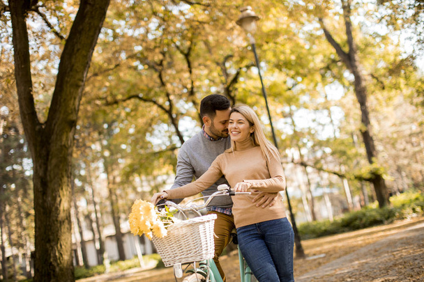 Aktiivinen nuori pari nauttii yhdessä romanttisessa kävelyssä polkupyörän kanssa kultaisessa syyspuistossa
 - Valokuva, kuva