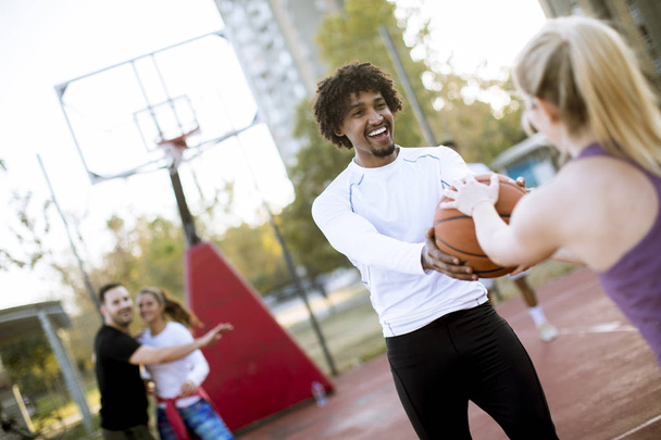 Pareja multiracial jugando baloncesto en la cancha al aire libre en el día outumn
 - Foto, Imagen