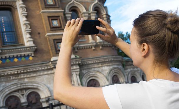 Женщина фотографирует церковь Спасителя на Крови со смартфоном
. - Фото, изображение