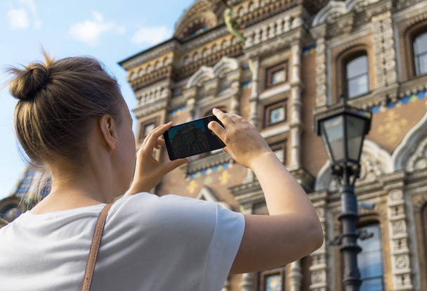Woman taking pictures of Church of the Savior on Blood with smartphone. - Photo, Image
