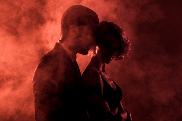 homme sensuel embrassant femme passionnée en fumée sur fond rouge
  - Photo, image