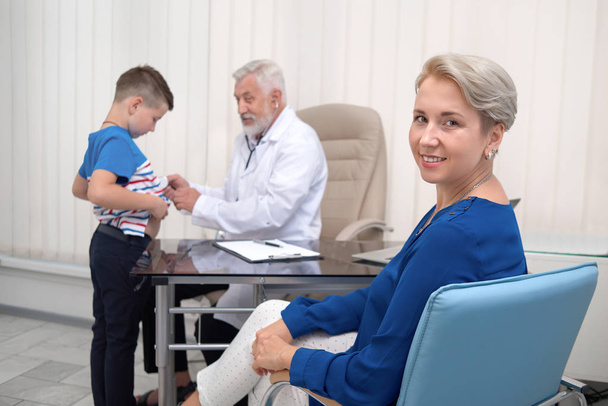 Mãe sorrindo, esperando médico examinando seu filho
. - Foto, Imagem