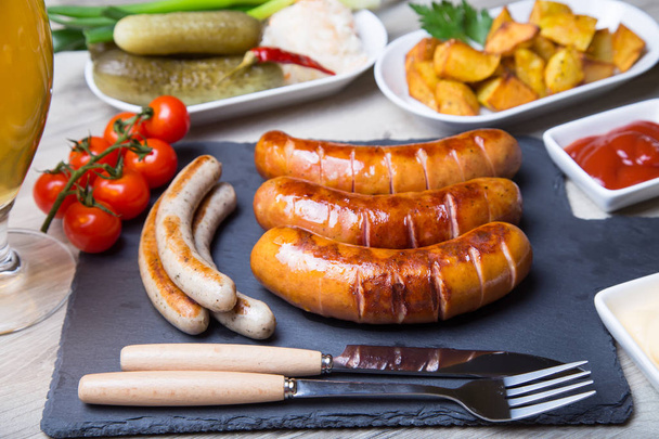 Grilled sausages with potatoes, cucumbers and sauerkraut, with two sauces. Close-up, selective focus. - Foto, imagen