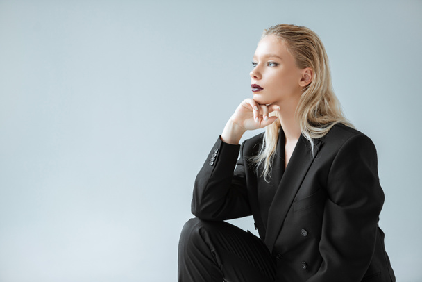attractive stylish girl posing in black suit for fashion shoot isolated on grey - Фото, зображення