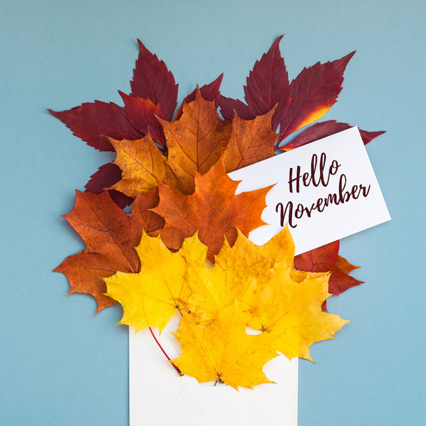 Creative Top view flat lay autumn concept composition. Envelope dried bright autumn leaves grey blue paper background copy space Square mock up fall thanksgiving wedding anniversary invitation cards - Photo, Image