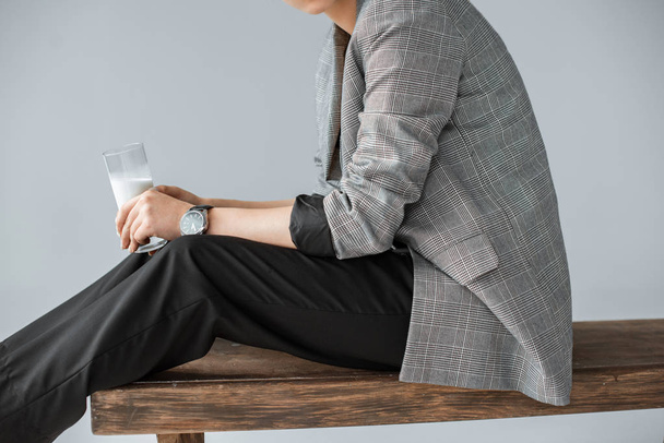 vista parziale della donna alla moda in giacca grigia con vetro di latte isolato su grigio
 - Foto, immagini