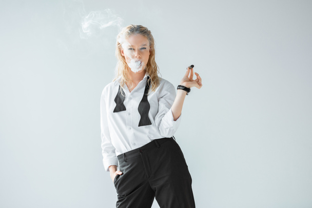 attractive stylish blonde girl smoking cigar isolated on grey - Fotó, kép