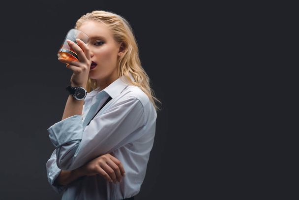 Módní elegantní dívka v formální oblečení drží sklenku whisky, izolované na tmavě šedá - Fotografie, Obrázek