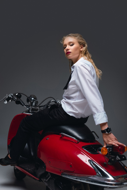hermosa chica de moda sentado en scooter rojo en gris
 - Foto, Imagen