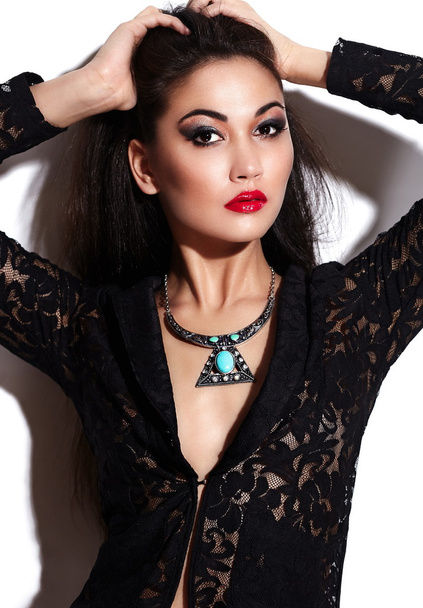 High fashion look.glamor closeup portrait of beautiful sexy stylish brunette Caucasian young woman model with bright makeup, with red lips, with perfect clean skin with jewelery in black cloth - Foto, imagen