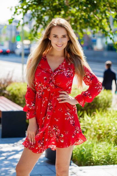 Portrait close up of young beautiful happy blonde woman in red dress, summer street outdoors - Foto, Imagem