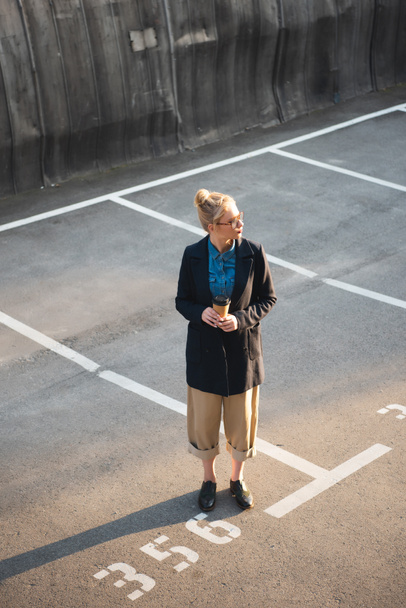 menina elegante atraente com café para ir de pé no estacionamento
 - Foto, Imagem