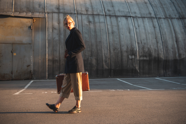 элегантная девушка с ретро чемоданом на городской парковке
 - Фото, изображение