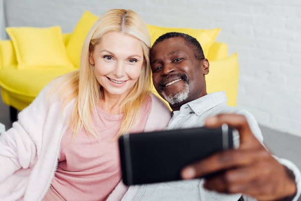 lachende volwassen vrouw en Afro-Amerikaanse man selfie te nemen - Foto, afbeelding