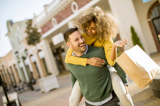 Portrait of  young man holds young woman on his back , have fun and go to shopping - Photo, Image