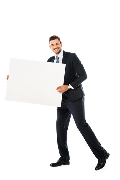 smiling businessman in suit showing blank poster with copy space isolated on white  - Zdjęcie, obraz