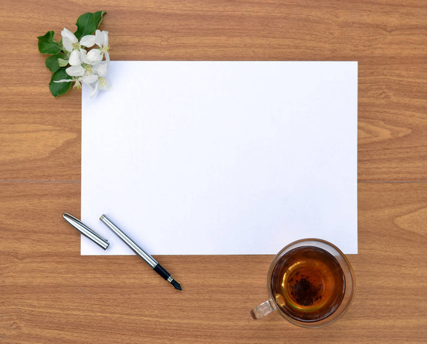 A clean sheet of paper on a wooden surface and a Cup of tea. - Photo, Image
