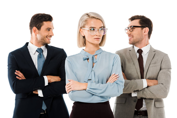 cheerful businessmen standing with arms crossed behind serious businesswoman isolated on white  - Фото, зображення