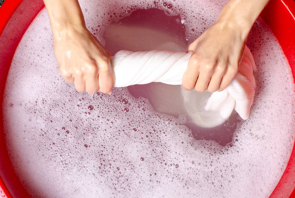 Women washing white sweater clothes in basin enemale powdered detergent - Foto, afbeelding