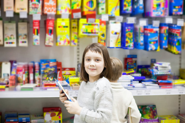 girl of 7 years old choosing stationery in   store. - Foto, Imagen