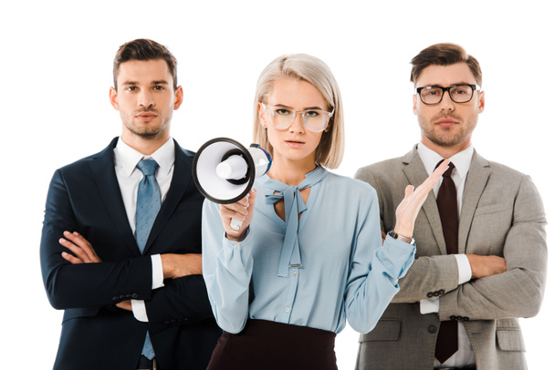 dissatisfied businesswoman holding megaphone while colleagues standing with arms crossed isolated on white - Foto, Bild