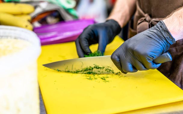 Male Chef Cutting Dill on Yellow Board - Kitchen Set - Foto, afbeelding